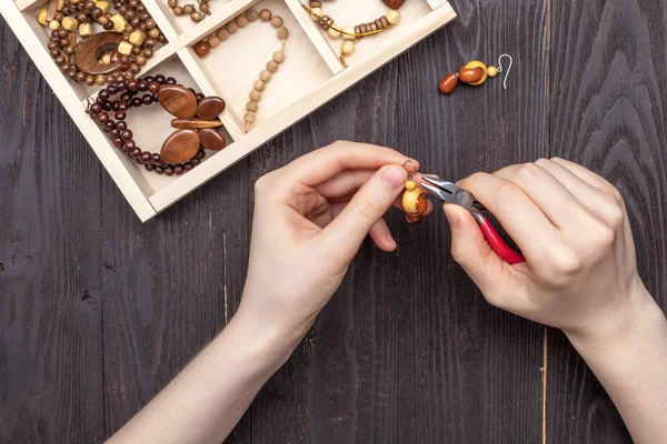 Handwerk thuis, het meisje maakt sieraden handen op tafel — Stockfoto