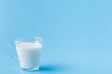Mavi bir arka plan üzerine bir bardak süt