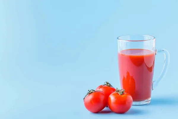 Tomates frescos y un vaso lleno de jugo de tomate — Foto de Stock