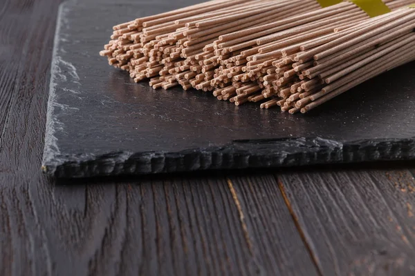 Getrocknete Buchweizen-Soba-Nudeln auf rustikalem Holzbrett — Stockfoto