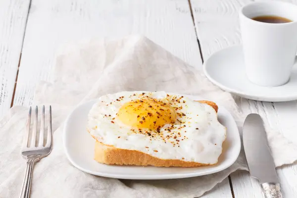 Pyszne śniadanie - gorące grzanki francuskie, stopiony ser Ementaler i smażone słonecznej stronie się jajko, podawane na talerzu biały filiżankę kawy na stole — Zdjęcie stockowe
