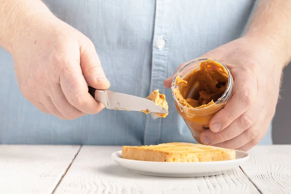 Adicionar a manteiga de amendoim de torrada rubicunda, mão, delicioso café da manhã — Fotografia de Stock