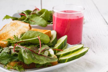 Rustik ahşap masada keçi peyniri, avokado, roka ve güneş kurutulmuş domates ile sağlıklı tost