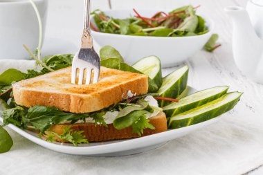 Rustik ahşap masada keçi peyniri, avokado, roka ve güneş kurutulmuş domates ile sağlıklı tost