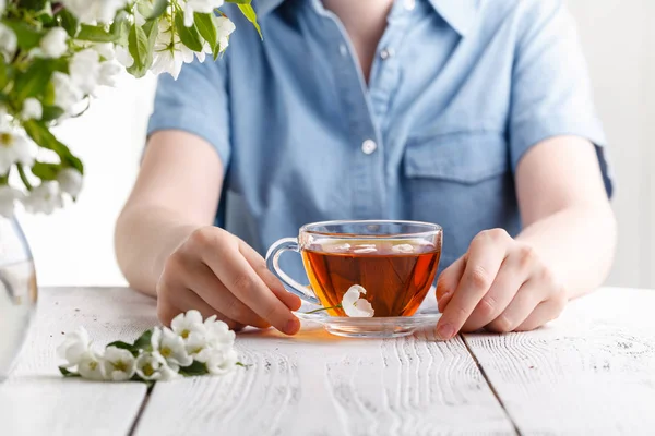 Menina tendo uma xícara de chá na mesa coberta com flor de macieira — Fotografia de Stock
