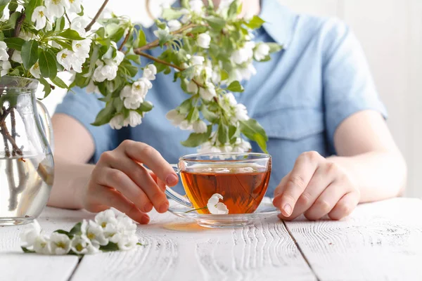 Menina tendo uma xícara de chá na mesa coberta com flor de macieira — Fotografia de Stock
