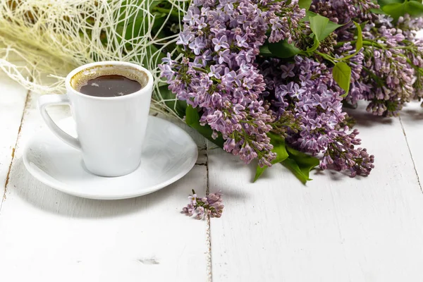 Filiżanka kawy i kolorowe kwiaty bzu na stół ogrodowy — Zdjęcie stockowe