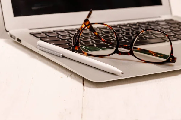 W rapor grafiğinde closeup siyah gözlük, kalem ve dizüstü bilgisayar — Stok fotoğraf