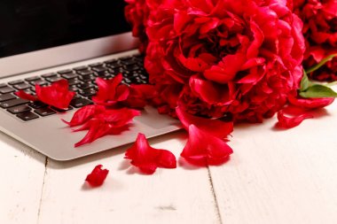 pembe şakayık, dizüstü bilgisayar, akıllı telefon, kalem, gözlük ve bir buket