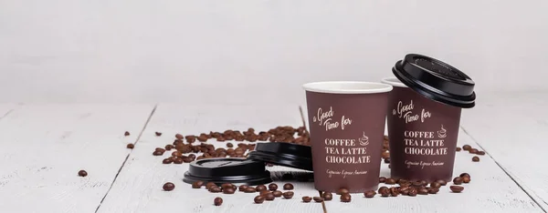 Паперова чашка кави та кавових зерен на білому дерев'яному фоні — стокове фото