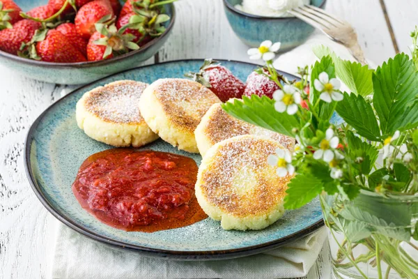 Cottage cheese pancakes (syrniki). Homemade cheesecakes from cottage cheese with sour cream, berries and milk. Traditional Russian dish. Close-up