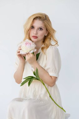 Beyaz ve gül rengi şakayıklar tutan güzel bir kızın kapalı çekimleri. Büyük buketli, çiçeklerinin tadını çıkaran bir kadın.