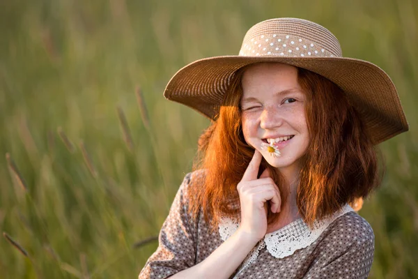感情的な赤毛の女の子はエレガントなドレスで日没時に夏の牧草地に草の中に立っています — ストック写真