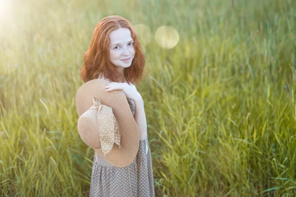 夏の草地で草の上で遊んでいる感情的な赤毛の女の子エレガントなドレスで日没時に — ストック写真