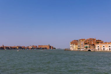 Venedik, İtalya, 11 Ağustos 2025: Giudecca ve Dorsoduro binalarıyla geniş kanal manzaralı. Venices Giudecca Kanalı 'nın her iki tarafında renkli tarihi binalar ve açık bir gökyüzü altında sakin tekne trafiği manzarası.