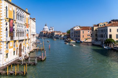 Venedik, İtalya, 11 Ağustos 2025: Büyük Kanal ve Santa Maria Della Salute manzarası. Tekneler Venices Büyük Kanalı boyunca geziyor. Kubbeli Santa Maria Della Salute 'u ve renkli tarihi binaları net bir şekilde görüyor..