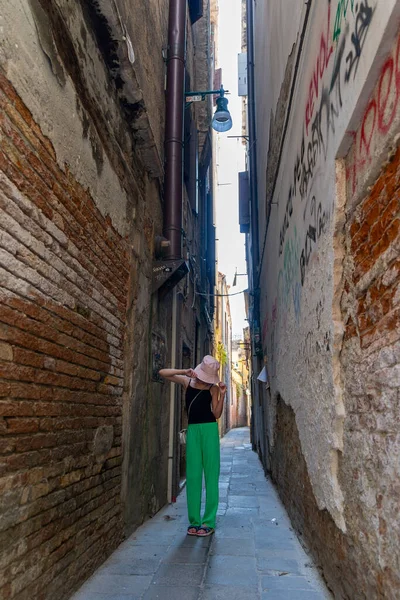 Venedik 'te dar bir sokağı keşfeden genç bir kız. Günlük giysiler içinde genç bir kız Venedik 'te dar bir duvar yazısıyla kaplı dar bir sokakta yürür ve sıra dışı bir şehir macerasını yakalar.