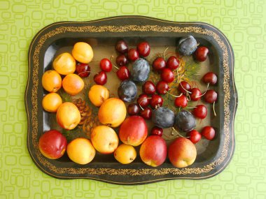 Büyük bir tepside erik, şeftali, kayısı ve kiraz.