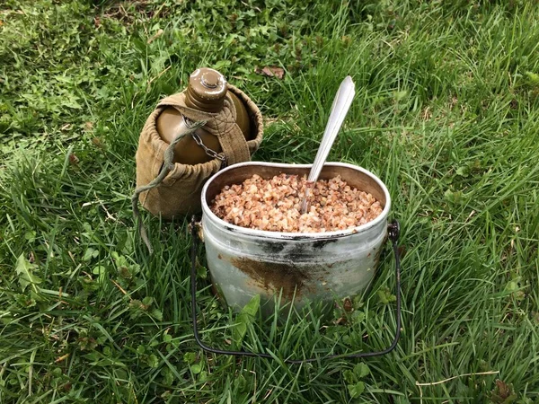 Une casserole de bouillie de sarrasin et une fiole d'eau. Kit de l'armée pour le déjeuner sur le terrain . Photos De Stock Libres De Droits