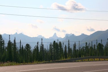 Kayalık tepelerle dağ sırasına giden yolu izle.