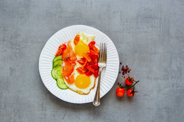 Düz plaka sabah kahvaltı somon füme, sahanda yumurta, domates ve salatalık ile açık beton renkli üstten görünüm üzerinde yatıyordu. İyi yağlar sağlıklı beslenme kavramı. 