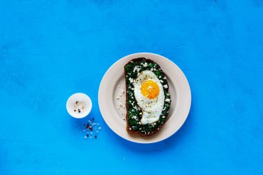 Parlak mavi zemin üzerine plaka çavdar ekmeği sandviç. Kale, kızarmış yumurta ve beyaz peynir üstten görünüm ile kahvaltı sandviç. Sağlıklı yeme, zayıflama, diyet yaşam tarzı konsepti. Düz yatıyordu stili.