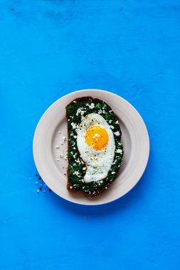 Parlak mavi zemin üzerine sağlıklı çavdar ekmeği sandviç. Kale, kızarmış yumurta ve beyaz peynir üstten görünüm ile kahvaltı sandviç. Sağlıklı yeme, zayıflama, diyet yaşam tarzı konsepti. Düz yatıyordu stili.