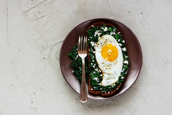 Kale, kızarmış yumurta ve beton arka plan üstten görünüm üzerinde beyaz peynir ile ev yapımı kahvaltı çavdar ekmeği sandviç. Sağlıklı yeme, zayıflama, diyet yaşam tarzı konsepti. Düz yatıyordu stili.