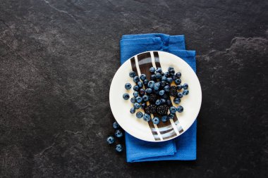 Organik Yaban mersini ve blackberry düz-lay, tabak taze siyah dut taş arka plan, superfood ve detoks kavramı. Üstten görünüm