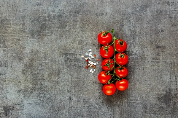 Kiraz domates ve deniz tuzu düz yatıyordu. Pişirme malzemeleri. Üstten görünüm. Koyu arka plan üzerinde çiğ Biyo gıda.