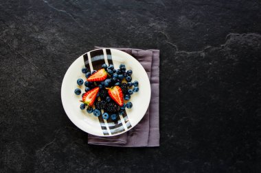 Plaka organik Berry. Taze çilek, yaban mersini ve blackberry düz yatıyordu. Taş arka plan, superfood ve detoks konsept üzerine yaz meyveleri karışımı. Üstten görünüm