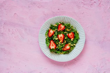 Vegan çilek roka çam fıstığı ve pembe kopya alan arka plan üzerinde mikro yeşillik salatası. Düz yatıyordu, en iyi görünüm. Superfood ve detoks kavramı.