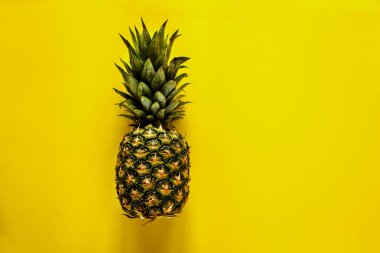 Ananas sarı arka plan düz üzerinde yatıyordu. Tropikal meyve yukarıdan. Yararlı doğal organik gıda. Bir tüm nesneyi. Stil minimalist.