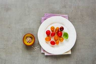 Domates salatası malzemeler düz-lay. Boşaltmak ile ışık arka plan üzerinde renkli domates plaka, fesleğen ve deniz tuz. Üstten görünüm