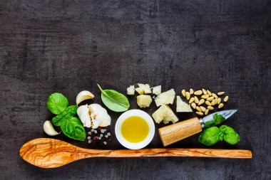 Tahta kaşık ve organik maddeler için İtalyan pesto sos karanlık antika arka plan düz üzerinde yatıyordu. Üstten görünüm, kopya alanı.