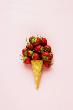 Bahar ya da yaz kompozisyon. Düz-lay gözleme tatlı koni üzerinde pastel açık pembe renkli taze çilek ile. Tatil ruh kavramı. Üstten görünüm.