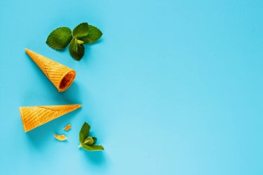 Bahar ya da yaz kompozisyon düz yatıyordu. Çerçeve tatlı waffle koniler pastel açık mavi renkli taze yaprakları nane ile yapılmış. Tatil ruh kavramı. Üstten görünüm.