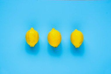 Üç tüm organik limon mavi renkli düz üzerinde yatıyordu. Üstten görünüm, gıda kompozisyonu
