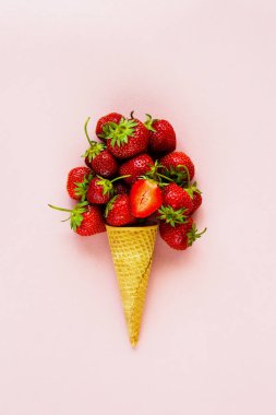 Bahar ya da yaz kompozisyon. Tatlı waffle koni üzerinde pastel açık pembe renkli taze çilek ile. Tatil ruh kavramı. Düz yatıyordu, en iyi görünümü.