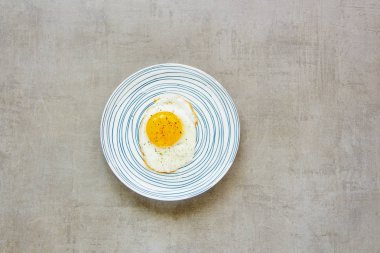Kahvaltı açık taş renkli düz tabağa kızarmış yumurta yatıyordu. Gıda. Kahvaltı. Sağlıklı gıda. Üstten görünüm