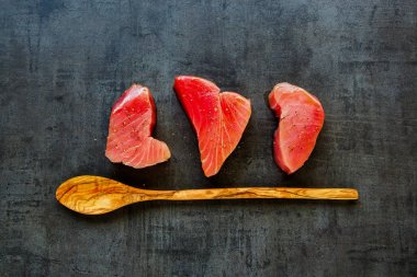 Düz tahta kaşık ve taze ton balığı bifteği vintage zemin üzerinde yatıyordu. Sağlıklı yemek. Gıda kavramı. Üstten görünüm