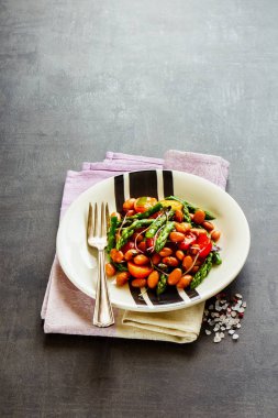 Vegan fasulye salatası koyu arka plan üzerine kapatın. Ev yapımı enerji aspargus, mikro yeşillik ve domates salatası artırılması. Temiz beslenme, superfood, vegan, gıda kavramı detoks. 