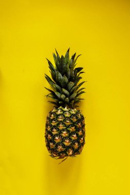 Düz ananas sarı zemin üzerinde yatıyordu. Tropikal meyve yukarıdan. Yararlı doğal organik gıda. Bir tüm nesneyi. Stil minimalist.