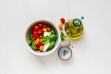 Caprese salatası kase ve malzemeler düz içinde yatıyordu. Domates mozzarella fesleğen yaprakları ve zeytin yağı. İtalyan mutfağı. Akdeniz mutfağı.
