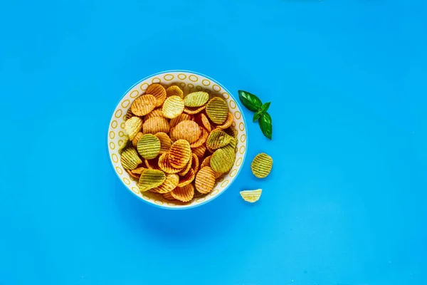 Healthy veggie chips on blue background flat lay