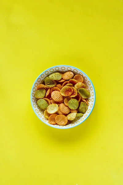 Veggie chips on yellow background flat lay