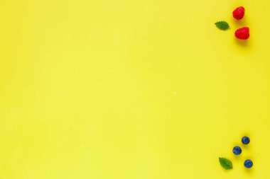 Ahududu, yaban mersini ve nane yapılmış yaratıcı düzen sarı zemin üzerine bırakır. Gıda kavramı. Düz yatıyordu, en iyi görünümü