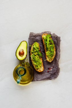 Fresh toasts with avocado and arugula flat lay. Good fats raw healthy eating concept. clipart