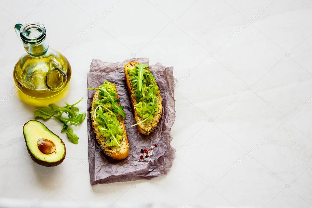 Fresh avocado toasts with arugula close up. Good fats raw healthy eating concept.