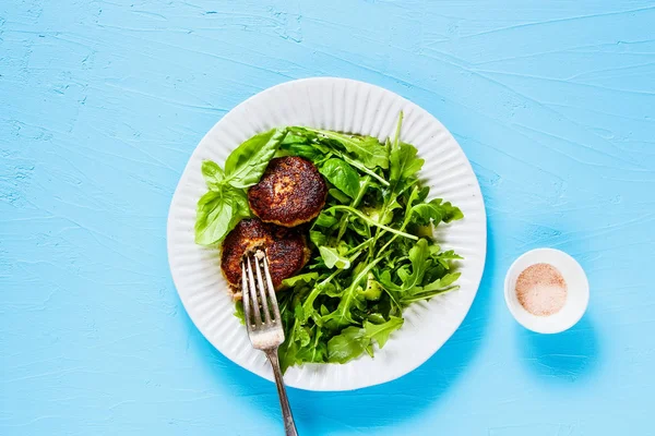 フラットを置く健全なカツレツと青の背景にルッコラのサラダ — ストック写真